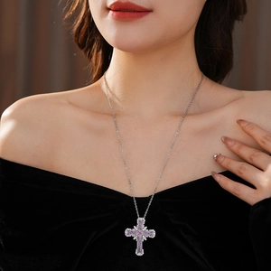 Close-up of elegant zircon cross pendant with purple gemstone on silver chain