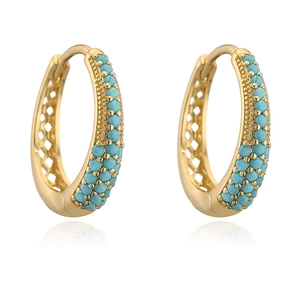 Close-up of gold-plated U-shaped earrings with turquoise beads and hollow diamond patterns