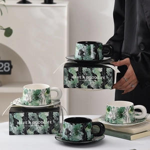 Floral ceramic coffee cup and saucer gift set in black and white with green flower patterns
