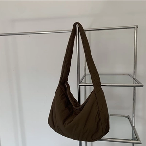 Brown padded nylon crescent tote bag with wide strap on minimalist display
