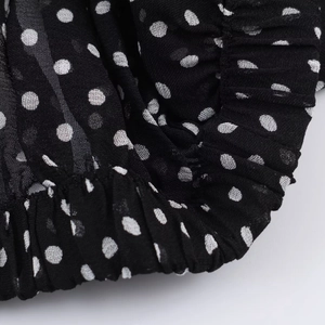 Dettaglio macro del tessuto nero a pois bianchi con orlo elastico plissettato e morbido