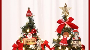 Close-up of mini Christmas tree with warm LED lights, red bows and golden ornaments