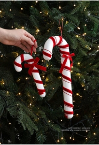 Detail of red and white candy cane ornament with velvet bow on a Christmas tree