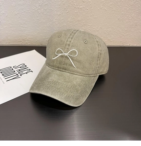 Détail d'une casquette en coton délavé vert olive avec broderie de nœud blanc