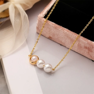 Close-up of elegant gold pearl necklace on a pink velvet jewelry box with ribbon