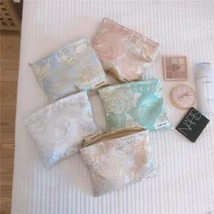 Detailed overhead view of floral jacquard cosmetic bags in pastel colors with gold zippers