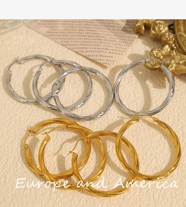 Detail of twisted hoop earring set in gold and silver finish on vintage backdrop