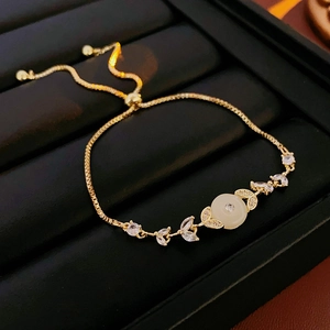 Dettaglio del bracciale regolabile placcato oro con pietra bianca e accenti di foglie