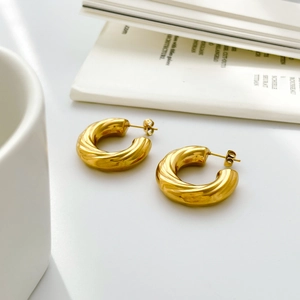 Detailed close-up of golden chunky twisted C-shaped earrings with a polished finish