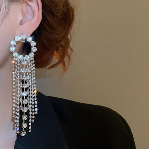 Close-up of elegant silver tassel earrings with sparkling rhinestones on model ear