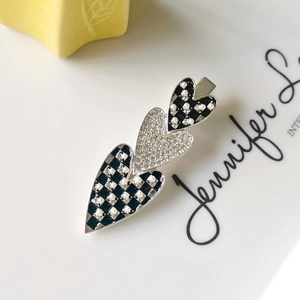 Detail of heart-shaped hair clip with black and white checkers, pearls and rhinestones