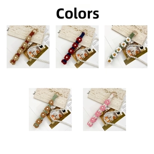 Detail of five multi-colored handmade crochet daisy flower keychains with gold metal rings