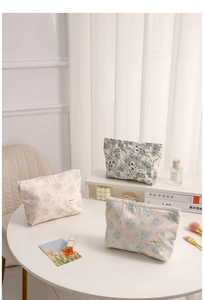 Detailed view of floral canvas makeup bags on a table with perfume and brushes