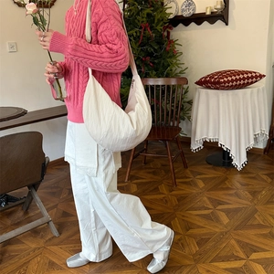 Minimalist large white canvas crescent crossbody bag worn by a model in a cozy room