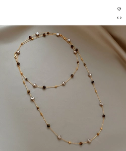 Détail d'un collier en plaqué or 18k avec œil de tigre et perles sur tissu soyeux