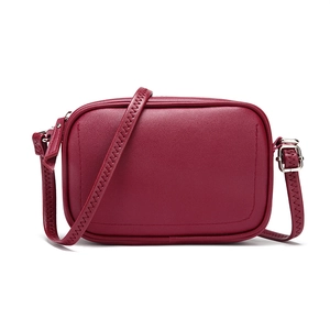Detail of burgundy leather camera bag featuring unique zigzag stitching on the strap