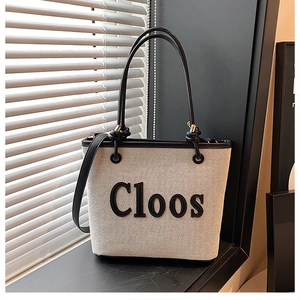 Detail of canvas tote bag featuring Cloos embroidery and black leather trim accents
