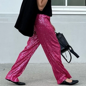 Detailed texture of sparkling rose pink sequins on wide-leg trousers for party wear