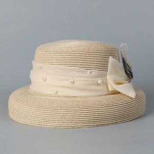 Detailed texture of beige straw sun hat featuring chiffon bow and pearl embellishments
