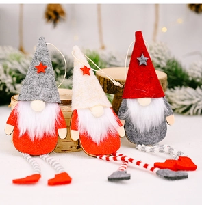 Close-up of three handmade Christmas gnomes with striped legs on a wooden stand