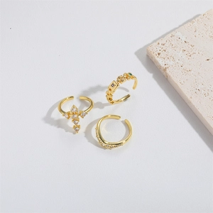 Three-piece gold cross rings with zircon stones on a minimalist stone display