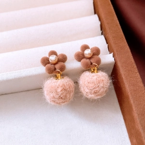 Nahaufnahme brauner Beflockungs-Blumenohrringe mit Perlen und rosa Bommeln