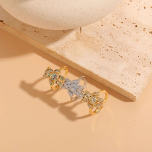 Detailed shot of three bear-shaped zircon rings in gold and silver on a beige stone surface