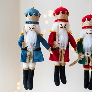 Three nutcracker soldier hanging ornaments with fabric details for Christmas tree decoration