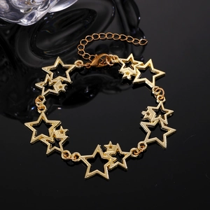 Détail du bracelet gourmette en or avec étoiles et fermoir mousqueton sur surface miroir