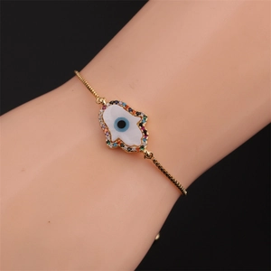 Dettaglio del bracciale Hamsa placcato oro con zirconi colorati indossato sul polso