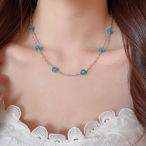 Dettaglio della collana con perle di cristallo a fragola indossata sul collo