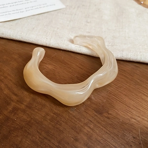 Macro view of creamy marble-patterned acrylic cuff with irregular wave design
