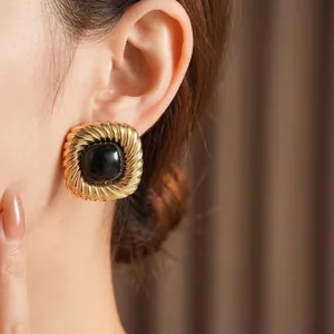 Orecchini vintage quadrati dorati con pietra nera indossati da una modella
