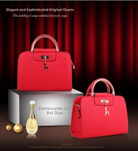 Detail view of red embossed handbag with gold metal handle and elegant deer pendant