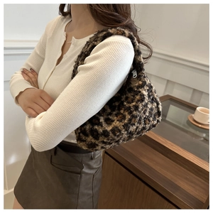 Detail of plush leopard print crescent bag with zip closure styled on a female model