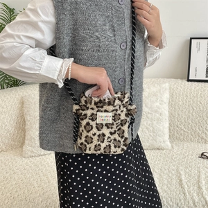 Detail of plush leopard print crossbody bag with striped drawstring and brand label