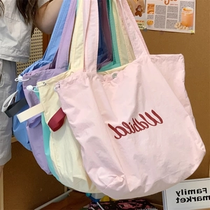 Close-up of drawstring canvas tote bags in various macaron colors and wide straps
