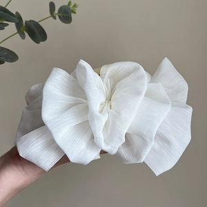 Detail of large white layered mesh bow hair claw clip with shimmering fabric texture