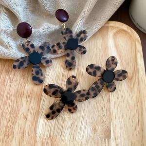 Close-up of leopard print floral earrings and headband on a minimalist wooden tray
