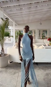 Detail of light blue halter dress featuring long tassels on a modern terrace