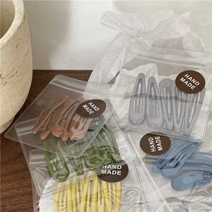 Macro shot of colorful drip oil teardrop hair clips set in handmade plastic packaging