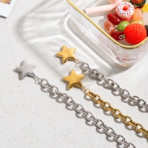 Star pendant titanium steel necklaces in gold and silver finishes on a grey textured surface