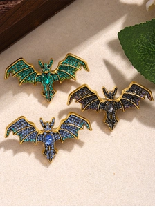Detailed view of vintage bat brooches in green, blue, and purple crystal inlay