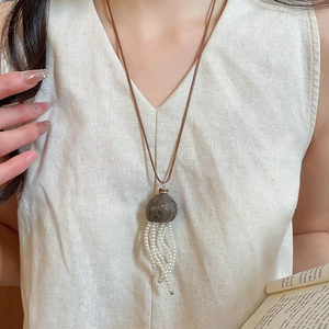 Detail of stone pendant with pearl tassels on a vintage aesthetic long necklace