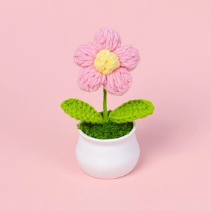 Handgehäkelte Puff-Blume im weißen Keramiktopf mit rosa Blütenblättern auf rosa Grund
