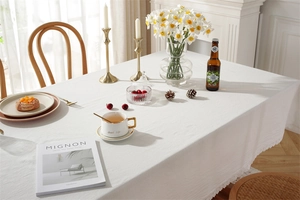 Detail of white cotton tablecloth with delicate lace borders and modern Nordic style
