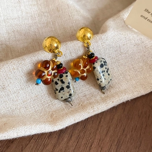 Detail of vintage flower earrings with natural stone and beads on beige linen