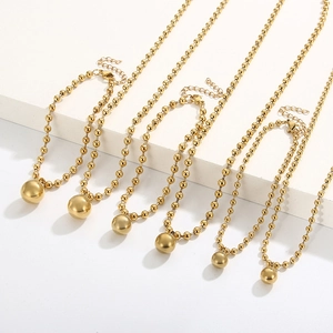 Polished gold beaded necklace and bracelet sets arranged on white geometric display stands