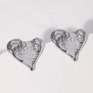Dettaglio di orecchini a cuore con texture lava argentata su una base in pietra naturale
