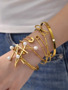 Macro shot of layered gold bracelets with pearl accent worn on wrist by a model